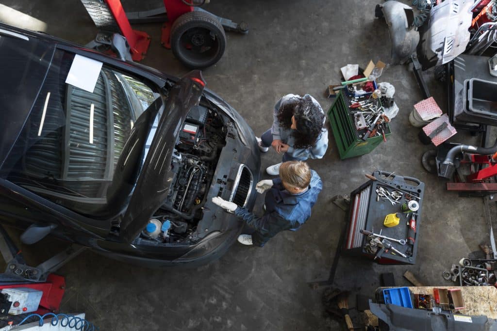 laudo-cautelar-mecanico-em-oficina-com-capo-do-carro-aberto-mostrando-para-a-motorista-o-motor